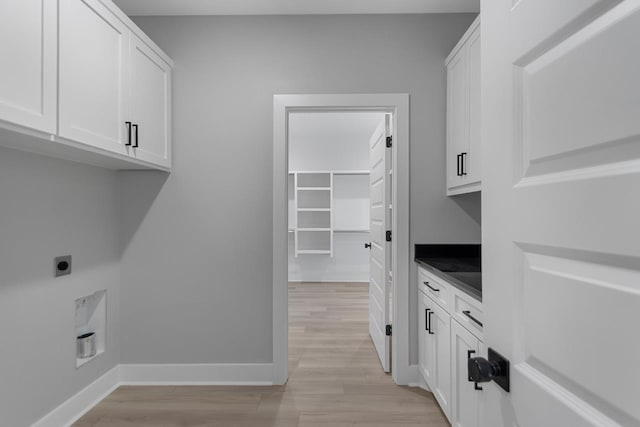 clothes washing area with cabinets, electric dryer hookup, and light wood-type flooring