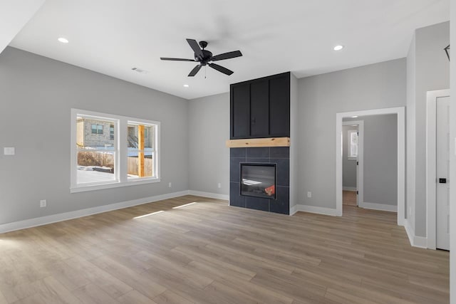 unfurnished living room with ceiling fan, light hardwood / wood-style flooring, and a tile fireplace