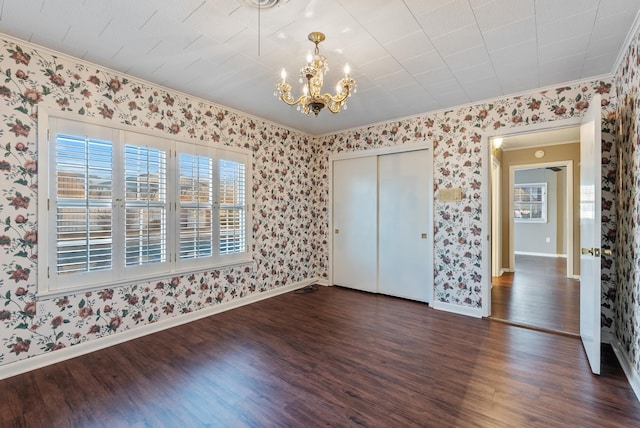 unfurnished bedroom with dark hardwood / wood-style flooring, crown molding, and a notable chandelier