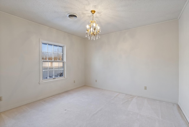 empty room featuring light colored carpet, a textured ceiling, and a chandelier