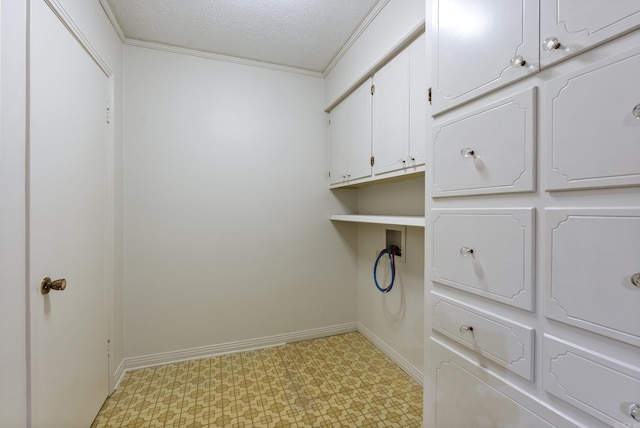 laundry area featuring cabinets, a textured ceiling, and ornamental molding