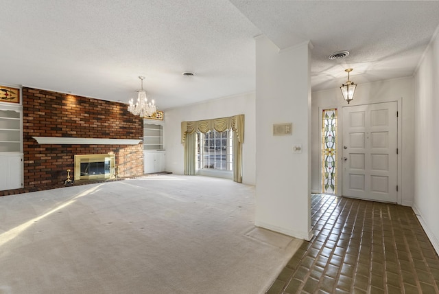 carpeted foyer entrance featuring a textured ceiling, an inviting chandelier, and a fireplace