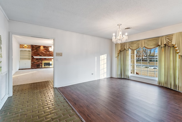 unfurnished room with a fireplace, an inviting chandelier, and a textured ceiling