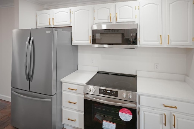 kitchen featuring white cabinets, stainless steel appliances, and ornamental molding