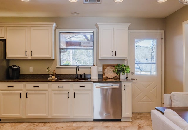 kitchen with sink, white cabinetry, stainless steel dishwasher, and dark stone counters