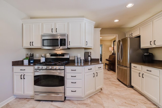 kitchen with white cabinets, appliances with stainless steel finishes, and dark stone counters