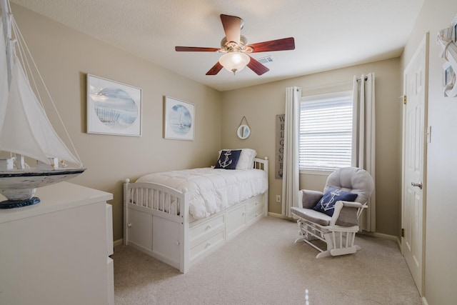 bedroom featuring ceiling fan, light carpet, and a textured ceiling