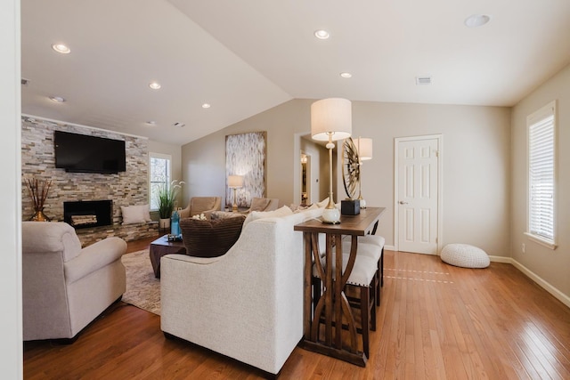 living room featuring lofted ceiling, a fireplace, and hardwood / wood-style flooring