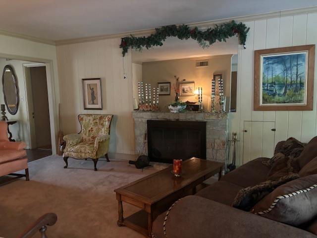 living room with ornamental molding and a stone fireplace