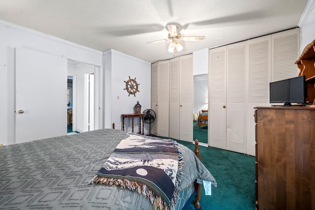 bedroom featuring a textured ceiling, dark colored carpet, ornamental molding, ceiling fan, and multiple closets