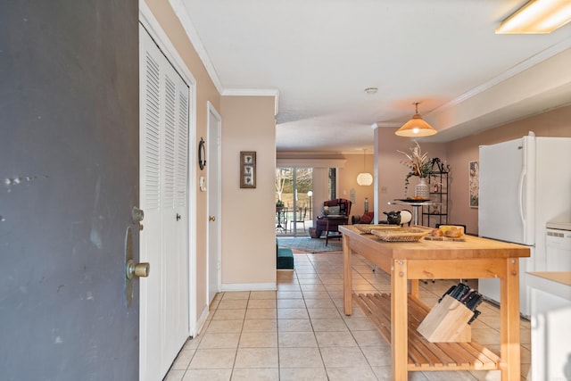 kitchen featuring white fridge, crown molding, light tile patterned floors, and pendant lighting