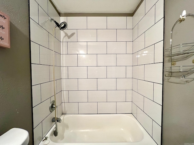 bathroom with toilet and tiled shower / bath