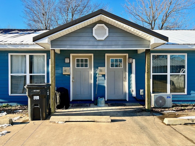 view of exterior entry with a porch and ac unit