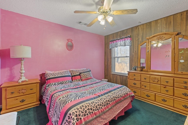 bedroom with a textured ceiling, ceiling fan, carpet flooring, and wooden walls