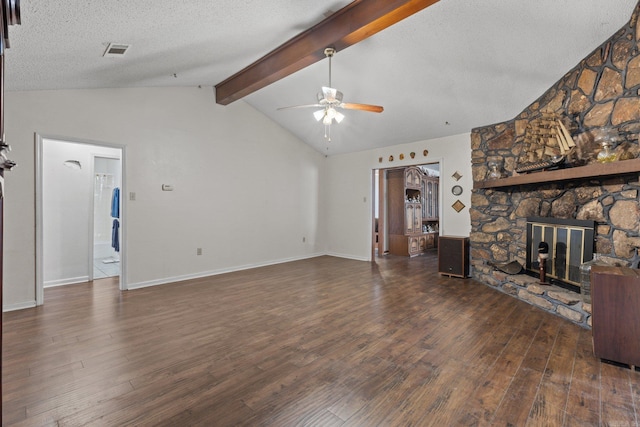 living room featuring lofted ceiling with beams, dark hardwood / wood-style floors, and a stone fireplace