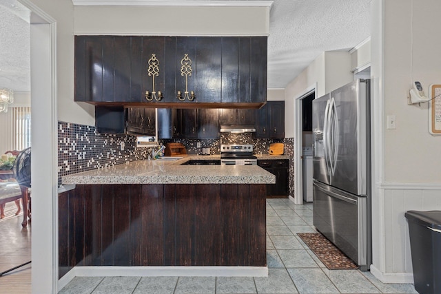 kitchen featuring kitchen peninsula, stainless steel appliances, dark brown cabinets, a textured ceiling, and sink