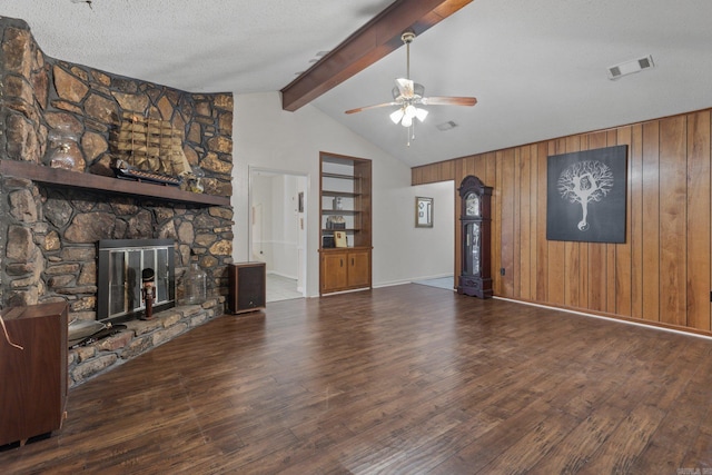 unfurnished living room with ceiling fan, wooden walls, a stone fireplace, a textured ceiling, and dark hardwood / wood-style flooring