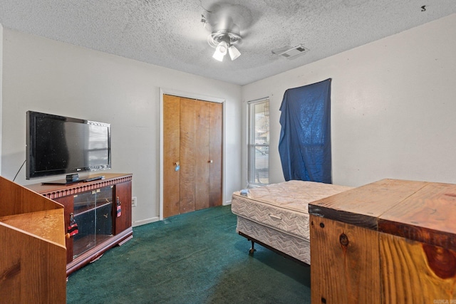 bedroom featuring a textured ceiling, ceiling fan, a closet, and dark carpet