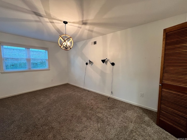 spare room featuring a chandelier and dark colored carpet