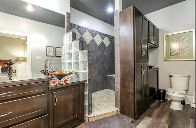 bathroom featuring toilet, a tile shower, and vanity