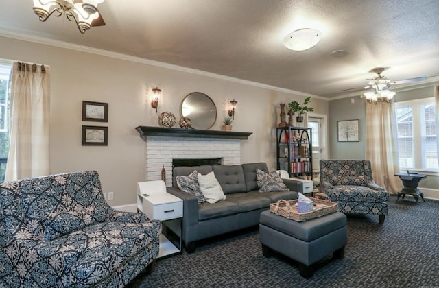 living room with a brick fireplace, a textured ceiling, ornamental molding, ceiling fan with notable chandelier, and dark carpet