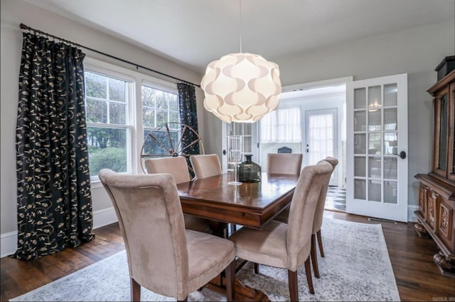 dining space with french doors, dark hardwood / wood-style flooring, and a chandelier