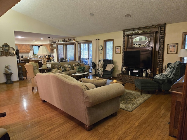 living room with a textured ceiling, lofted ceiling, and light hardwood / wood-style flooring