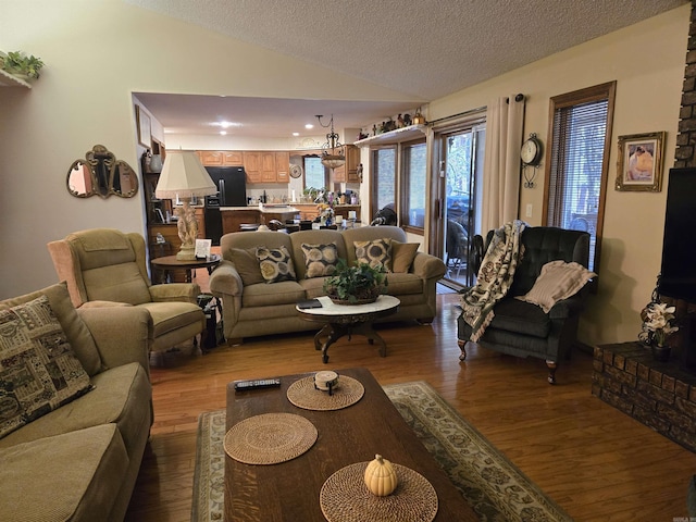 living room with a textured ceiling, vaulted ceiling, and light wood-type flooring