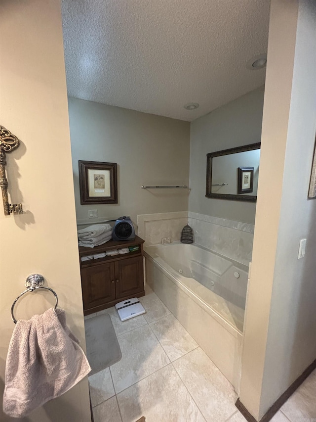 bathroom with a textured ceiling, tile patterned flooring, a bathtub, and vanity