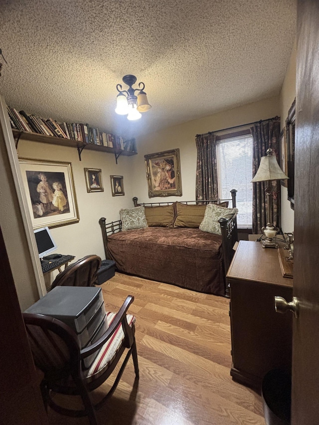 bedroom featuring a textured ceiling, hardwood / wood-style floors, and an inviting chandelier