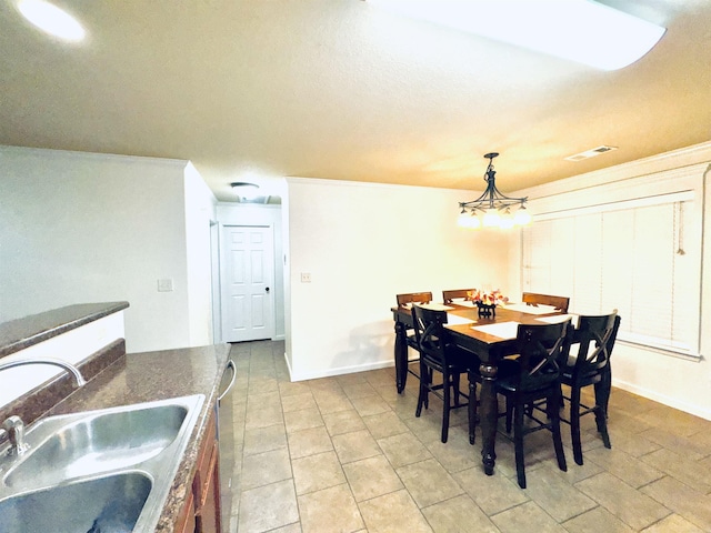 dining area featuring ornamental molding, a chandelier, and sink