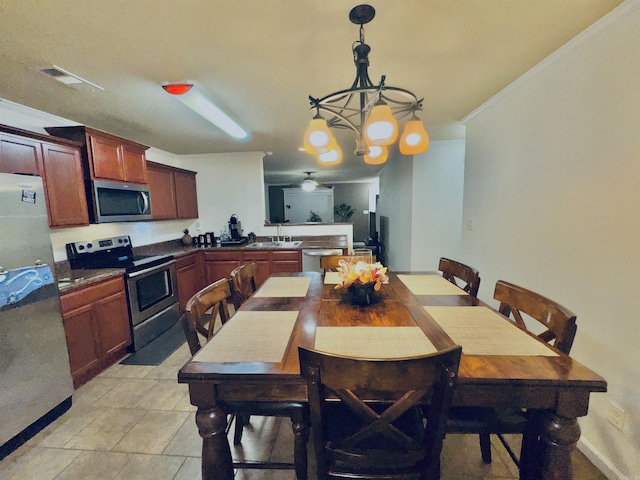 dining space with ornamental molding, sink, and an inviting chandelier