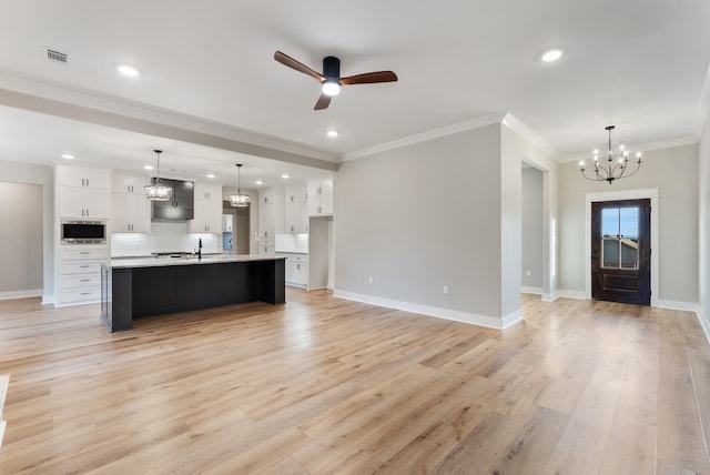 kitchen with built in microwave, white cabinetry, a spacious island, hanging light fixtures, and light hardwood / wood-style flooring