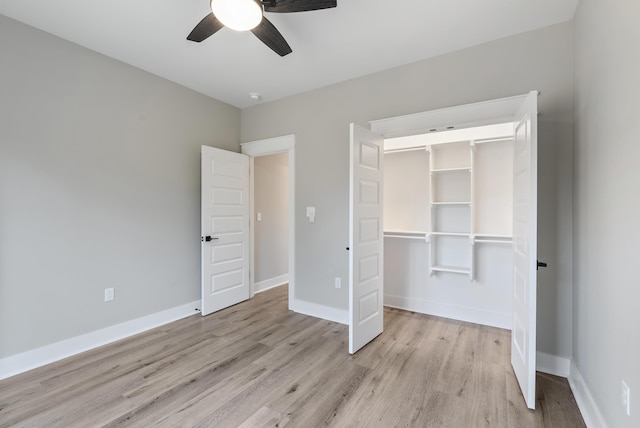 unfurnished bedroom featuring a walk in closet, a closet, ceiling fan, and light wood-type flooring