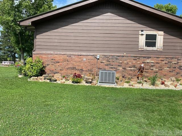 view of side of property featuring central air condition unit and a yard