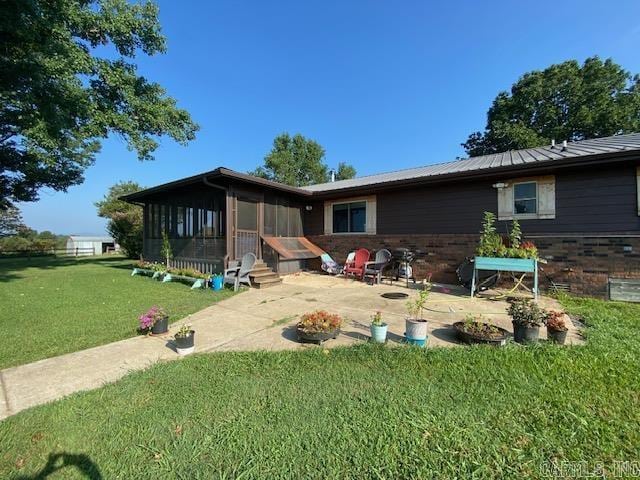 back of house with a lawn, a patio area, and a sunroom