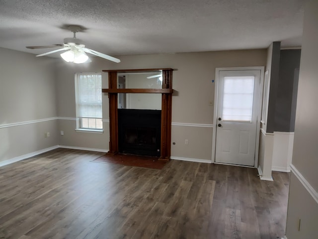 unfurnished living room featuring dark wood-type flooring, ceiling fan, and a textured ceiling