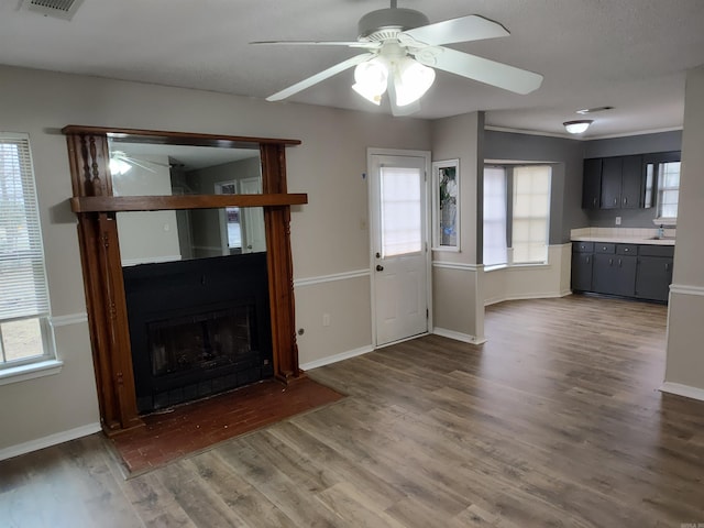 unfurnished living room with dark wood-type flooring, a wealth of natural light, sink, and ceiling fan