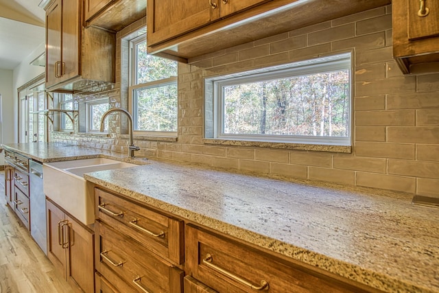 kitchen with light wood-type flooring, backsplash, and light stone counters