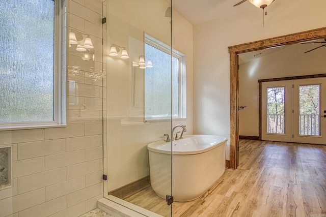 bathroom with a tub to relax in, plenty of natural light, and hardwood / wood-style floors