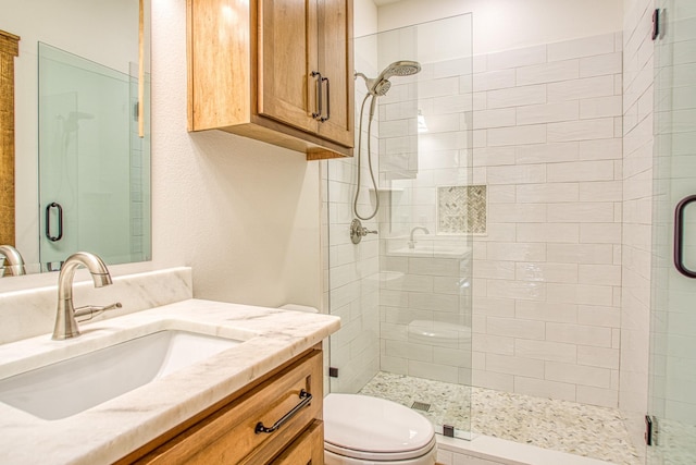 bathroom featuring a shower with shower door, toilet, and vanity