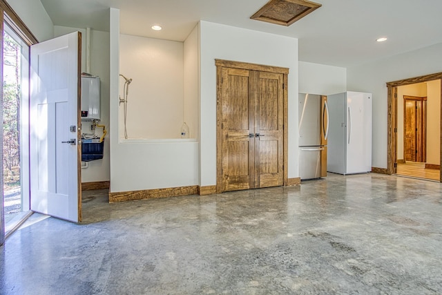 interior space with concrete flooring, water heater, and stainless steel refrigerator