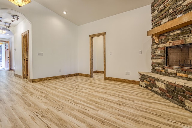 unfurnished living room with light wood-type flooring, lofted ceiling, and a fireplace