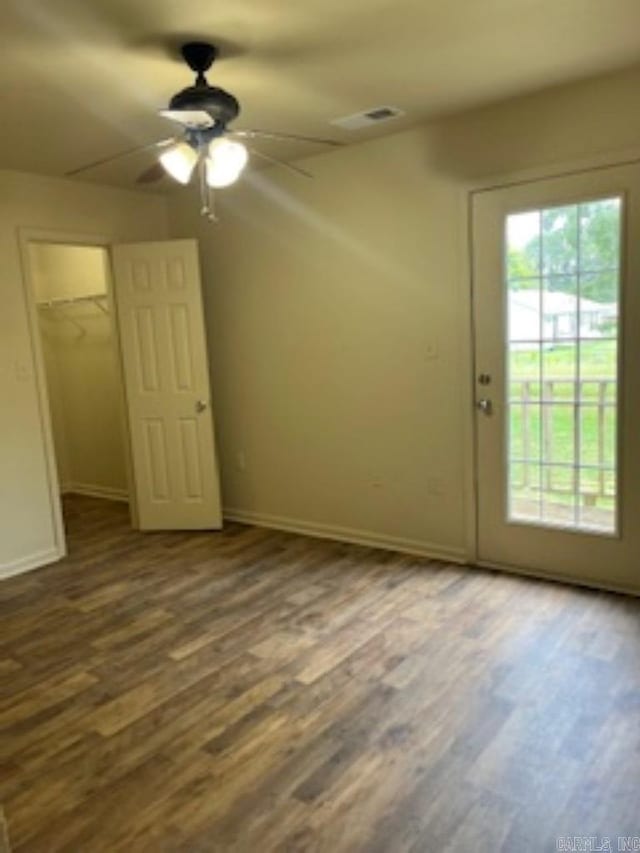 unfurnished bedroom with ceiling fan, wood-type flooring, a spacious closet, and a closet