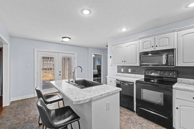 kitchen with black appliances, sink, white cabinetry, an island with sink, and french doors