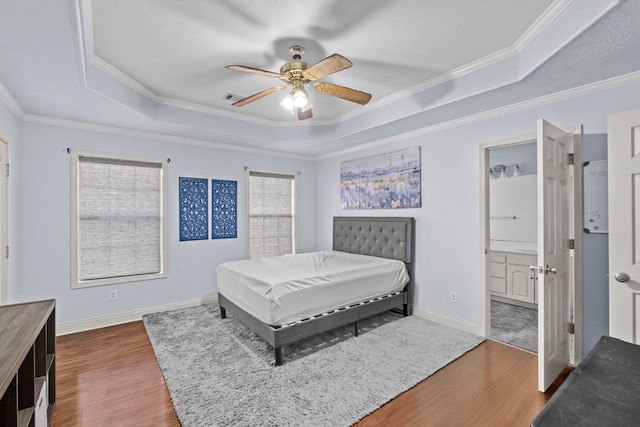 bedroom featuring dark wood-type flooring, ceiling fan, ornamental molding, and a tray ceiling