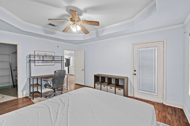 bedroom with ceiling fan, hardwood / wood-style floors, a tray ceiling, and ornamental molding