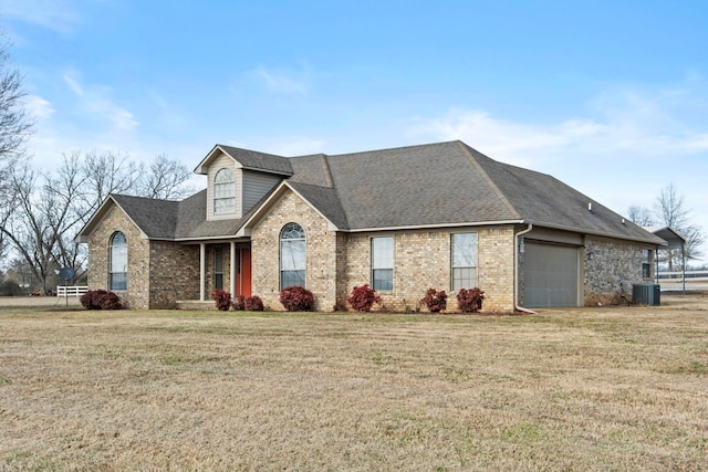 view of front facade featuring a front yard, central air condition unit, and a garage