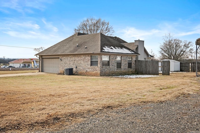 view of side of property featuring a garage, cooling unit, and a lawn