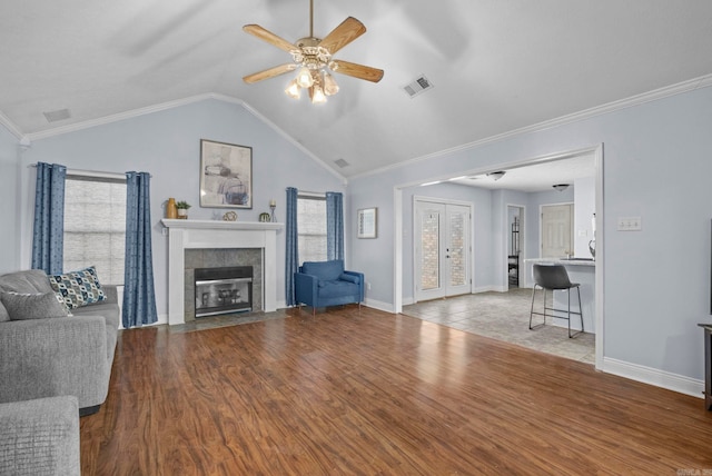 living room featuring a tiled fireplace, ornamental molding, lofted ceiling, and hardwood / wood-style flooring